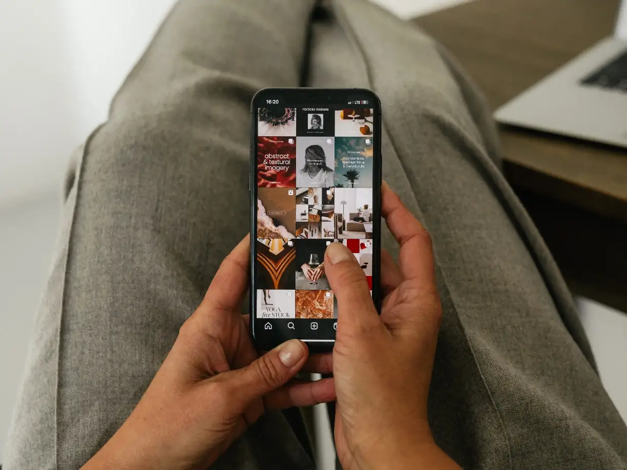 Hand hält Smartphone mit Social-Media-Profil, das mehrere Beiträge vom Online-Business zeigt.