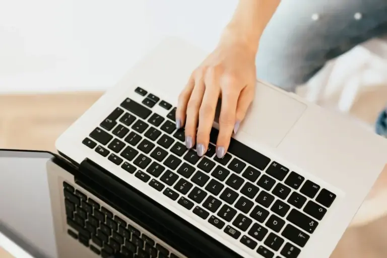 Hand mit lackierten Fingernägeln tippt auf einer Laptop-Tastatur